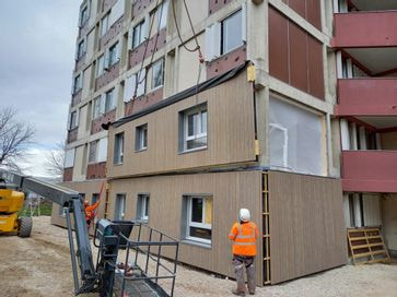 devanture d'un immeuble de logements avec un technicien en train de faire une manoeuvre