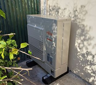 Pompe à chaleur installée contre le mur d'une maison individuelle