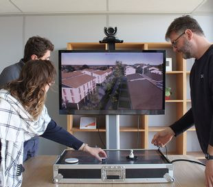 3 personnes en train de faire de la planification urbaine autour d'une table numérique qui modélise la ville en 3D