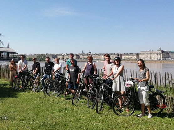 groupe de personnes qui pose avec leurs vélos sur les quais de la Garonne